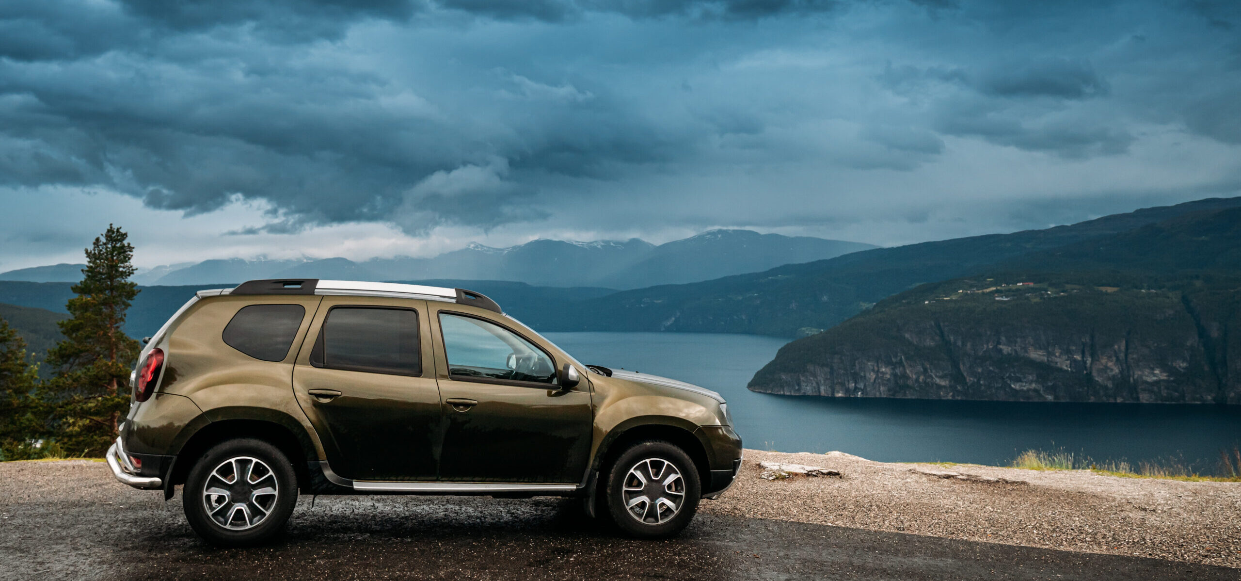 Utvik, Sogn Og Fjordane County, Norway. Car Suv Parked Near Scenic Route Road In Norwegian Mountain Lake Landscape. Innvikfjord Is A Sub-fjord Of Nordfjord.